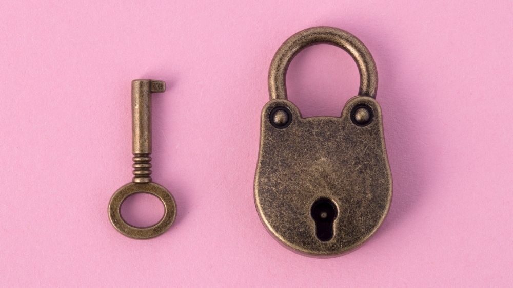 chastity lock and key on pink background